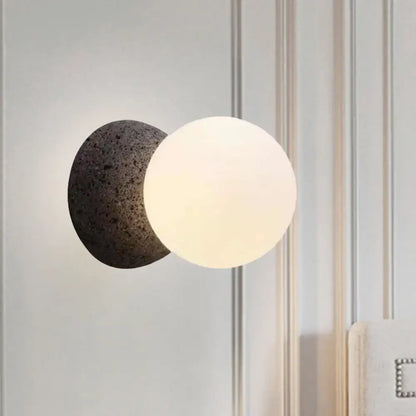 Minimalist wall sconce with matte black textured base and opaque white glass shade for bedroom light type