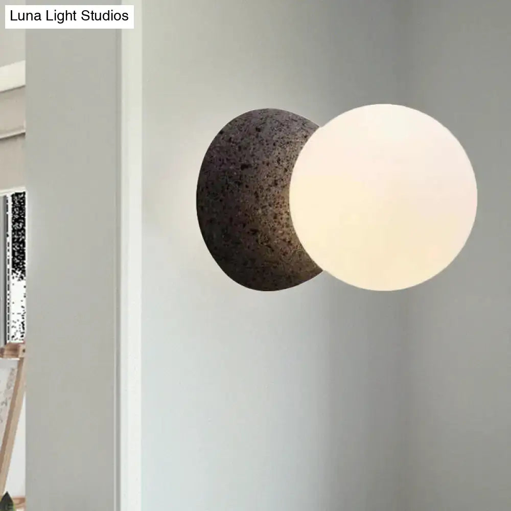 Minimalist black and white wall sconce with a dark stone base and frosted glass shade bedroom light type