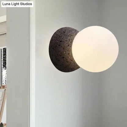 Minimalist black and white wall sconce with a dark stone base and frosted glass shade bedroom light type