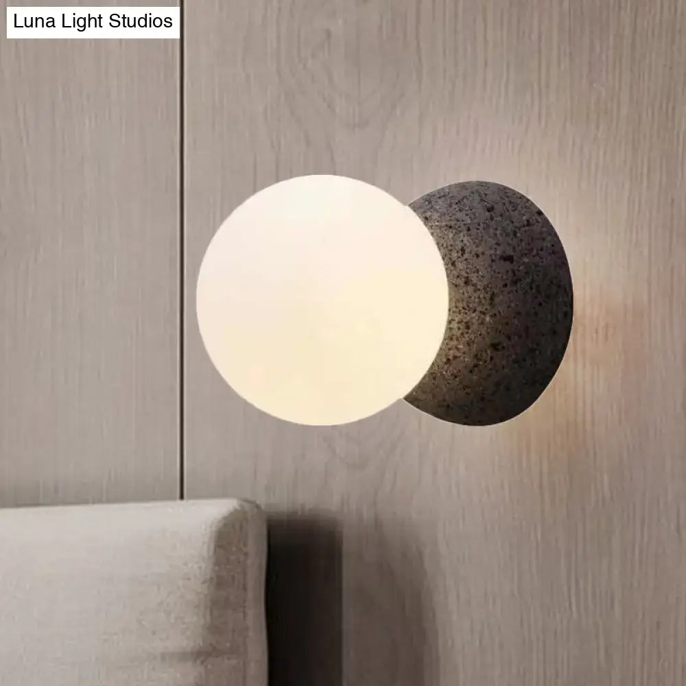 Minimalist black and white glass shade wall sconce with frosted globe and dark gray stone base light type for bedroom