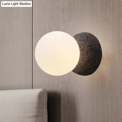 Minimalist black and white glass shade wall sconce with frosted globe and dark gray stone base light type for bedroom