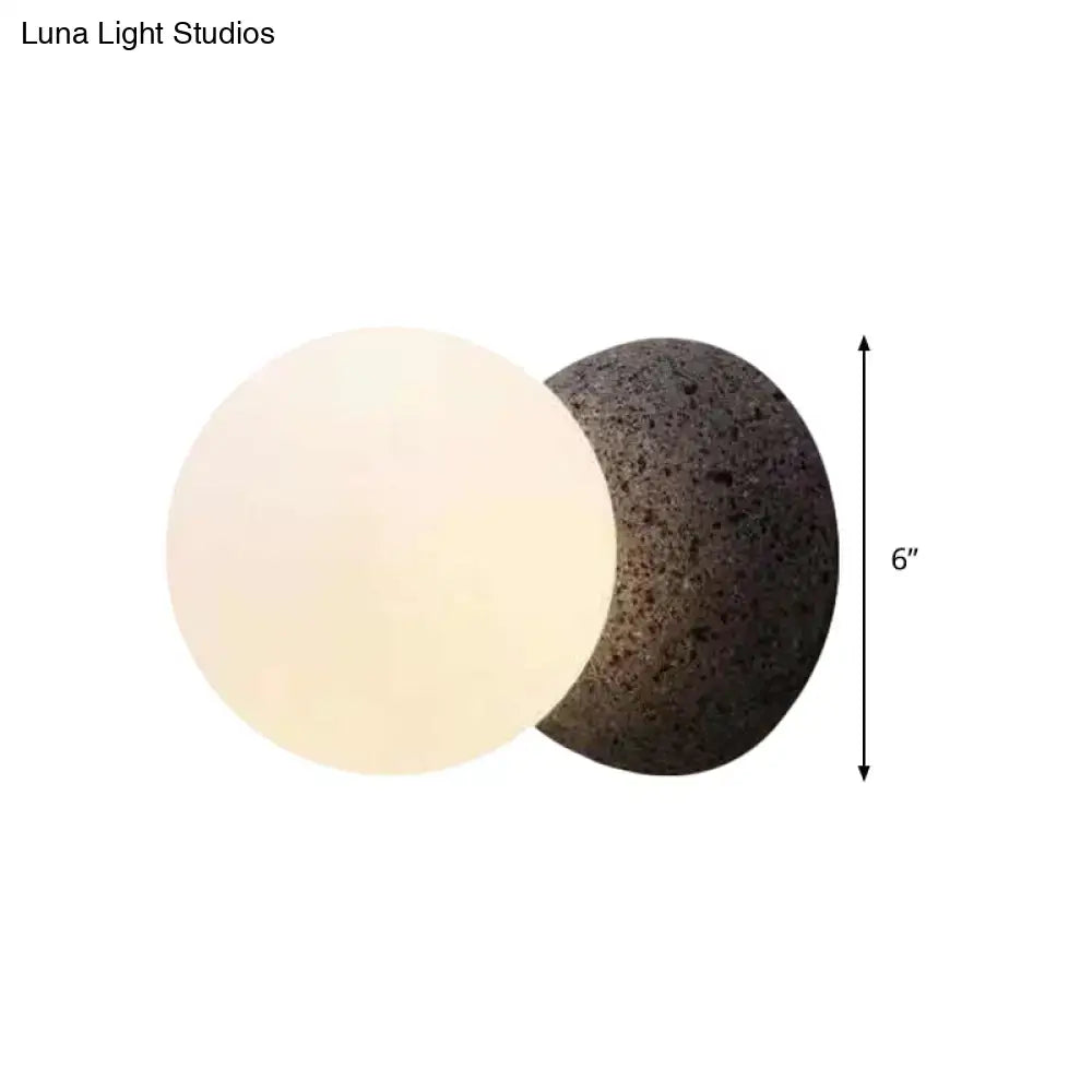 A minimalist dual-sphere table lamp with a smooth white glass shade and dark volcanic stone for bedroom light type