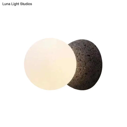 Minimalist black and white glass shade wall sconce with smooth off-white and dark gray volcanic stone light type