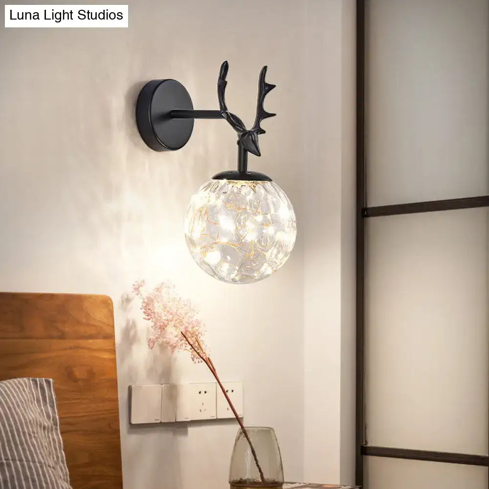 Black deer head wall sconce with minimalist black antlers and textured glass globe housing warm led lights for bedroom use
