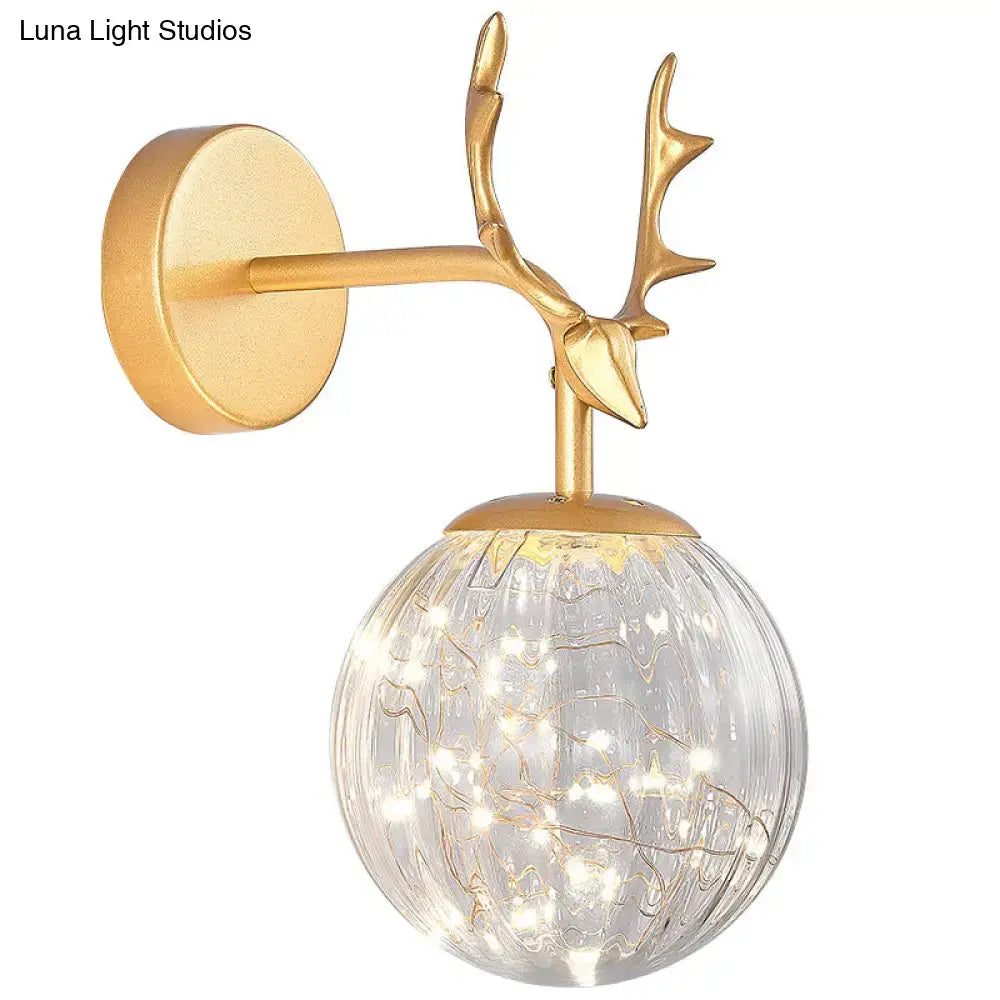 Gold-toned deer antler wall sconce with textured crackled glass globe and warm LED fairy lights for bedroom lighting