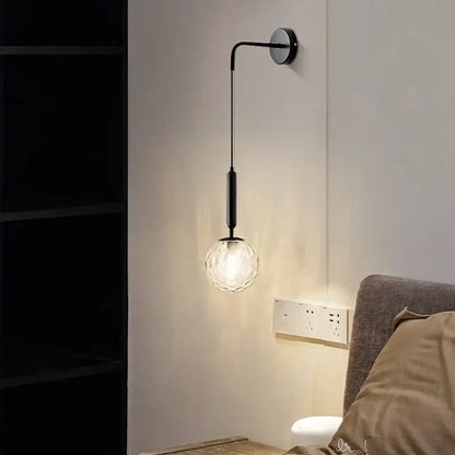 A sleek black metal wall lamp with a faceted decorbites glass ball globe for minimalist bedroom wall decor