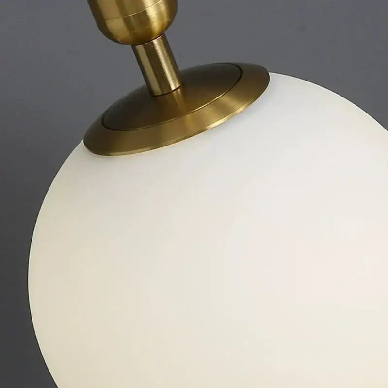 Minimalist black and brass decorbites glass ball wall lamp with a frosted white spherical glass ball wall sconce