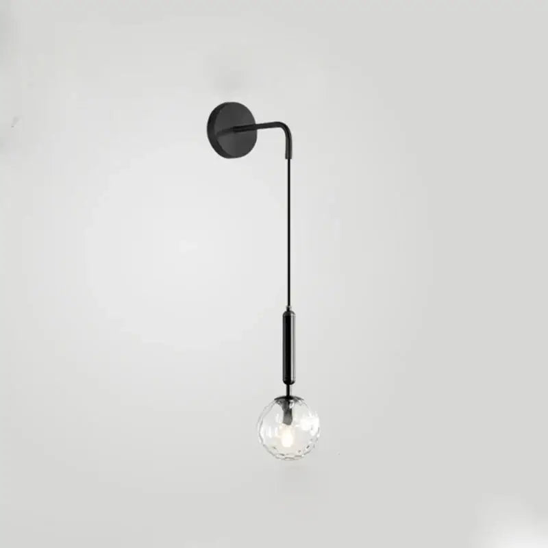 Minimalist black and brass glass ball wall lamp featuring a sleek curved arm and clear faceted decorbites glass ball bulb