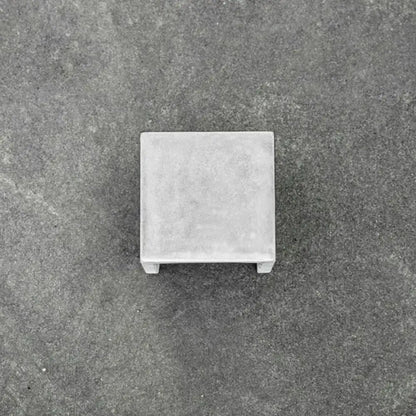 Gray concrete square pedestal with textured surface and small feet for minimalist black cement led wall lamp use