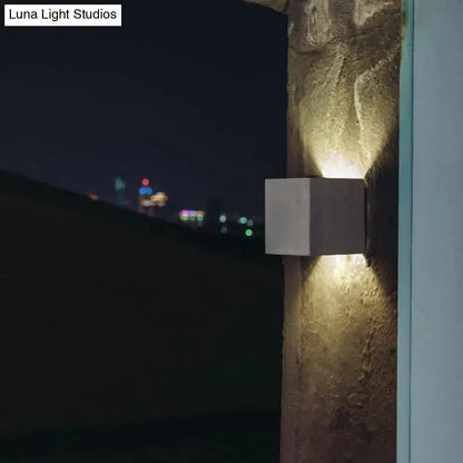 Minimalist black cement led wall lamp with modern concrete cube design emitting warm focused glow for living room