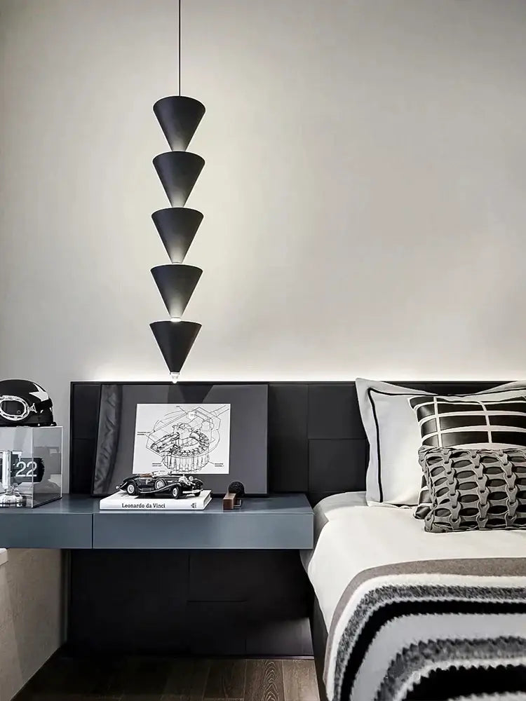 Minimalist black conical pendant light with stacked illuminated segments above a modern decorbites cream bedroom chandelier