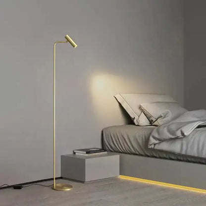 Gold-finished decorbites brass floor light with slender curved design and adjustable head for minimalist black bedroom decor