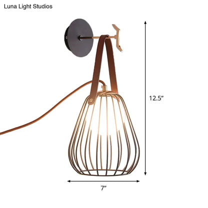 A modern wall-mounted lamp with black finish pear cage iron and teardrop-shaped shade with brown leather straps