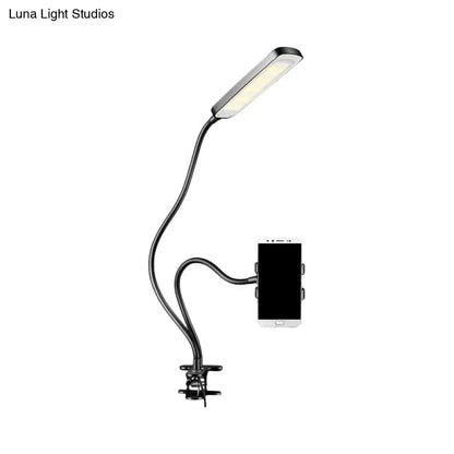 Minimalist black flexible arm desk lamp with sleek rectangular led head and integrated phone holder for bedroom use