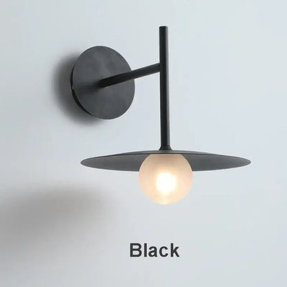 Minimalist black flying saucer wall lamp with matte finish, circular base, and illuminated globe bulb for bedroom decorbites flying saucer