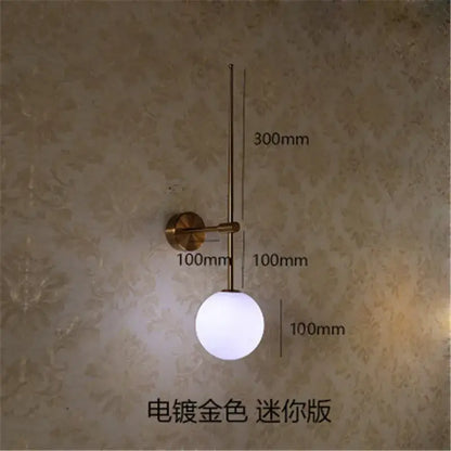 A minimalist black glass ball led wall lamp with brass-finished arm featuring a frosted glass globe for bedroom decorbites glass ball