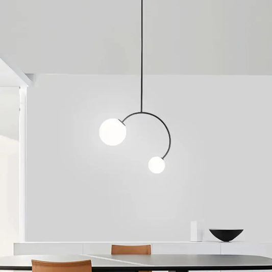 Minimalist black metal glass ball pendant lights with two frosted white bulbs on curved arm for dining room decorbites
