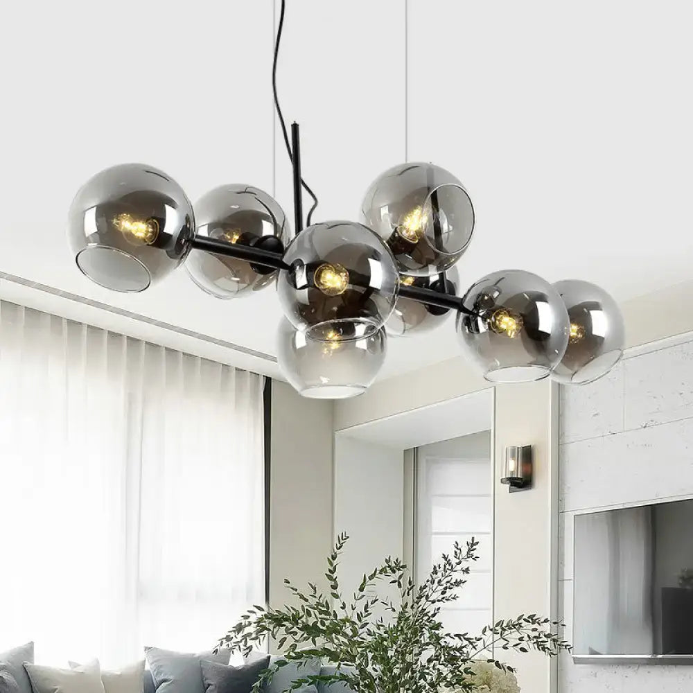 Minimalist black and gold chandelier with clear smoke grey glass spheres on black metal frame for dining room lighting