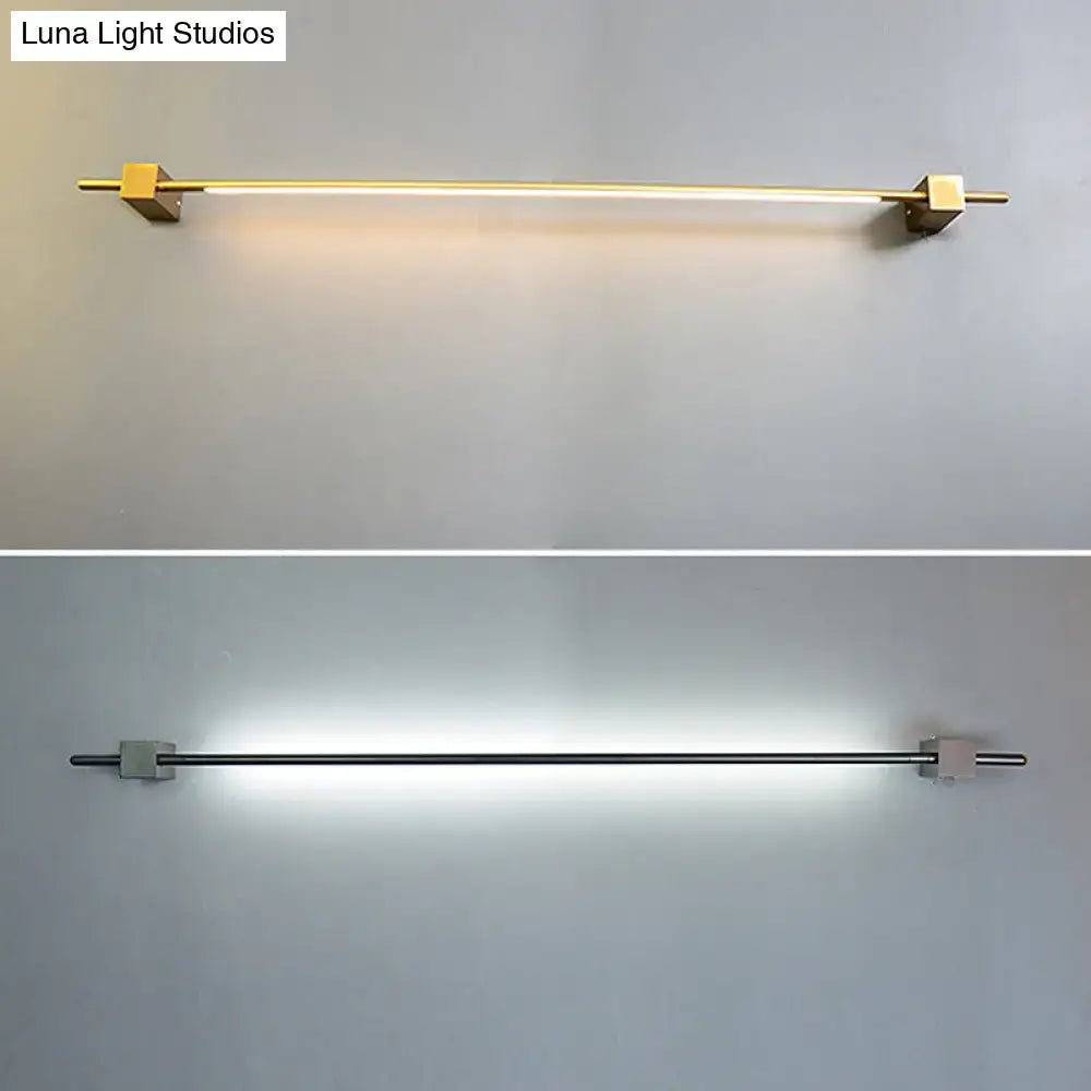 Modern minimalist black and gold wall lamp with slender bar design and brass end caps for living room fixture