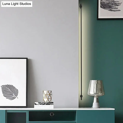 Minimalist black and gold feather wing wall light with slim led strip and soft green illumination for living room