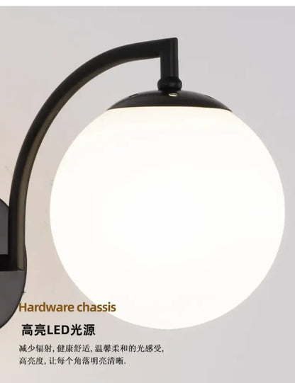 Black curved arm holding minimalist black and gold decorbites glass ball wall light with frosted spherical lamp