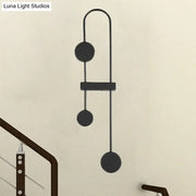 Black gold minimalist metal led wall sconce with sleek curved arms and three circular discs for bedroom lighting