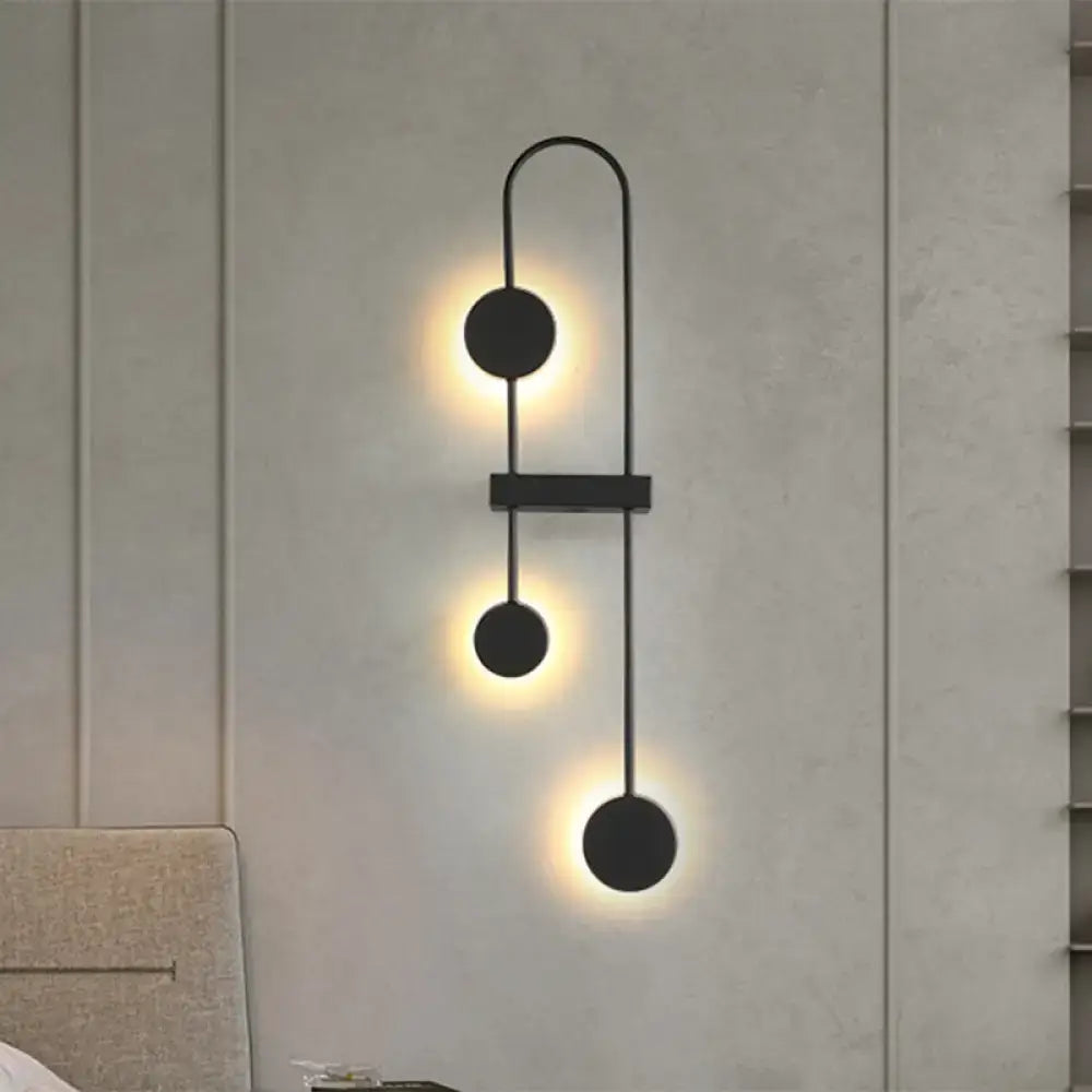 Minimalist black gold metal led wall sconce with three warm glowing circular fixtures for bedroom lighting