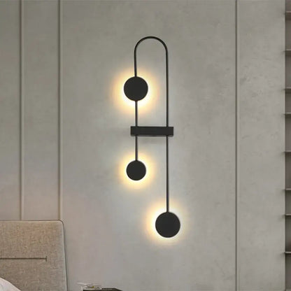 Minimalist black gold metal led wall sconce with three warm glowing circular fixtures for bedroom lighting