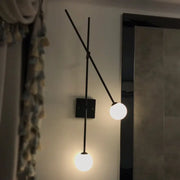 Minimalist black metal wall sconce with gold metal arm and two opal glass bubble globes for bedroom light fixture