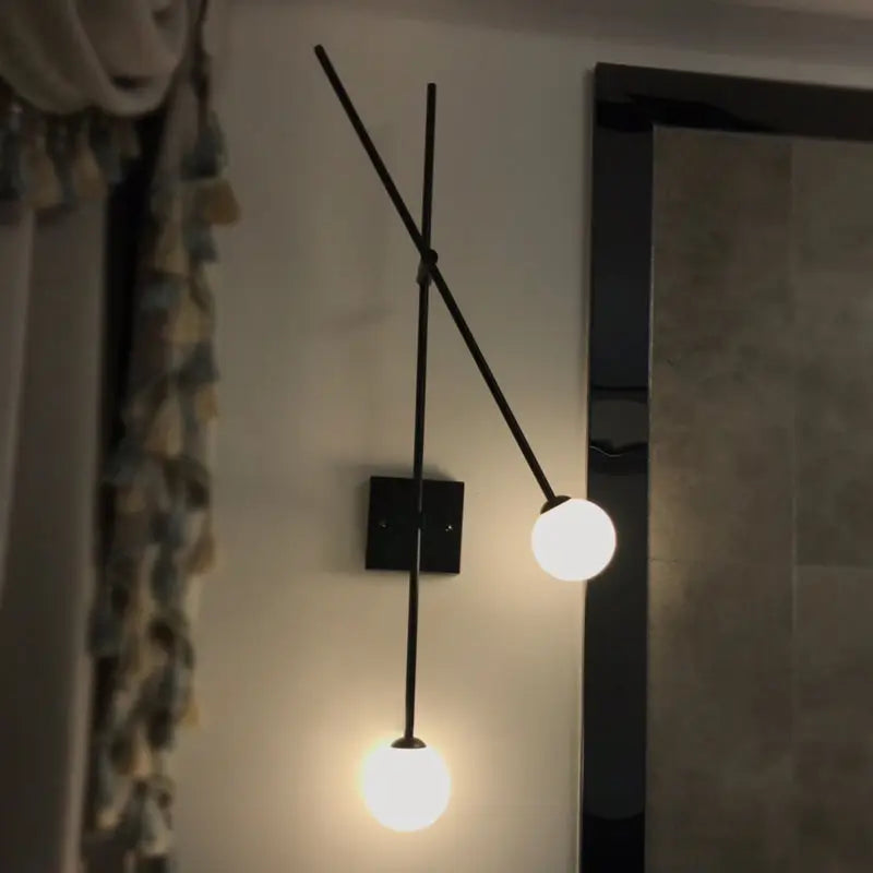 Minimalist black metal wall sconce with gold metal arm and two opal glass bubble globes for bedroom light fixture