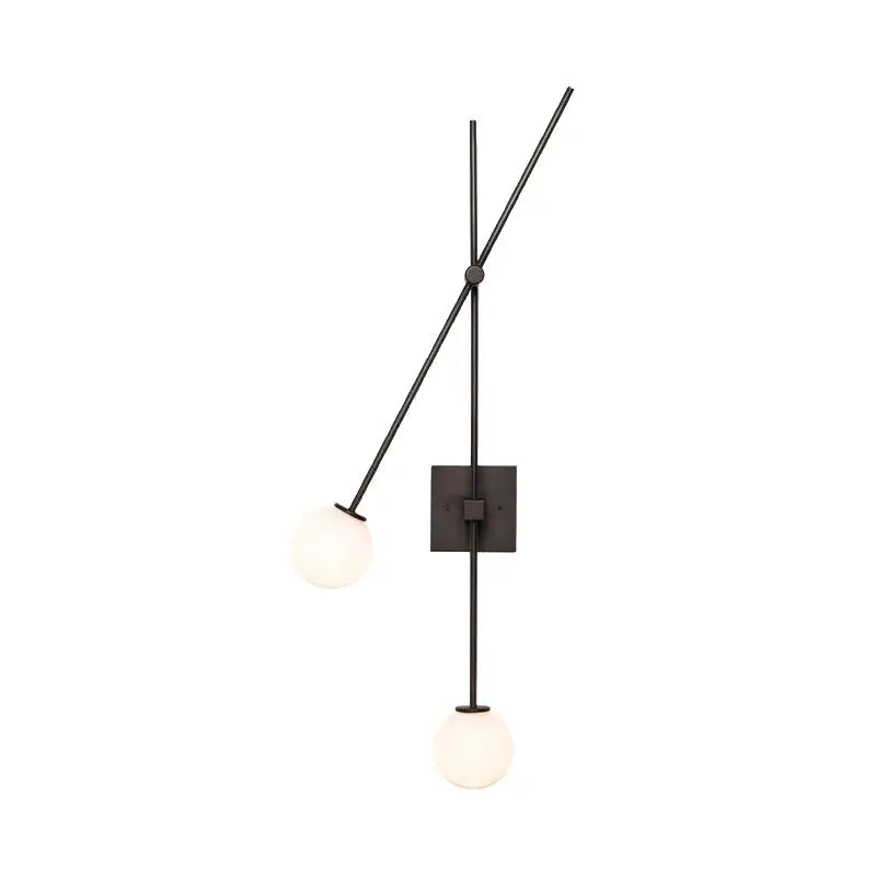 Minimalist black metal wall sconce with two frosted opal glass bubble shades and gold metal arms for bedroom light fixture