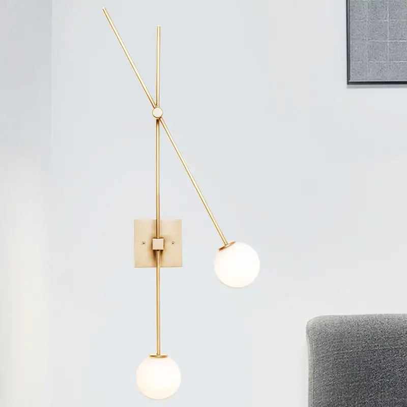 Minimalist black and gold light fixture with metal arm and opal glass bubble shades for bedroom sconce lighting