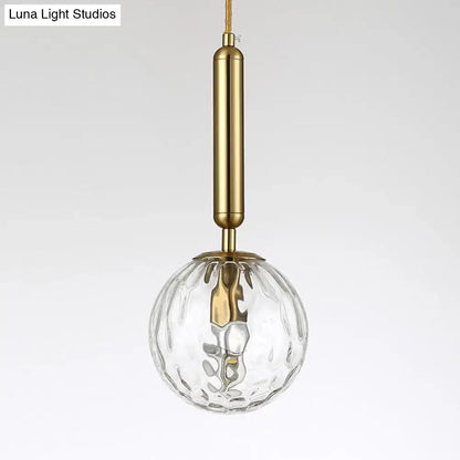 Minimalist black gold spherical wall sconce with clear textured glass globe and brass 10 inch fixture for bedroom