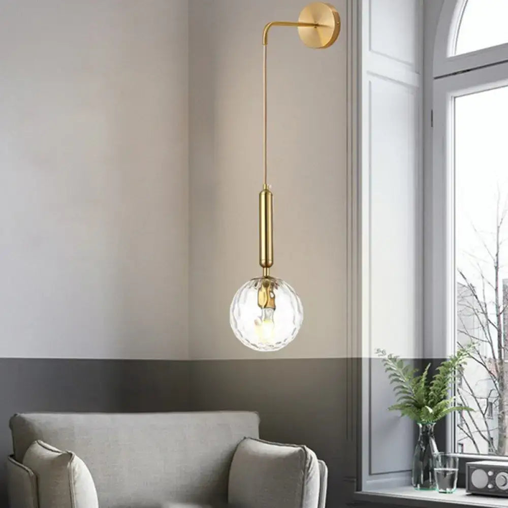 Minimalist black gold wall sconce with gold-toned inch fixture and faceted crystal glass globe shade for bedroom lighting