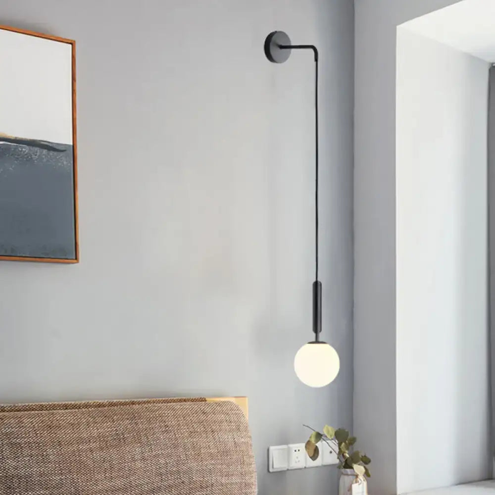 Minimalist black gold spherical wall sconce with frosted glass globe and sleek curved arm 10 inch fixture for bedroom