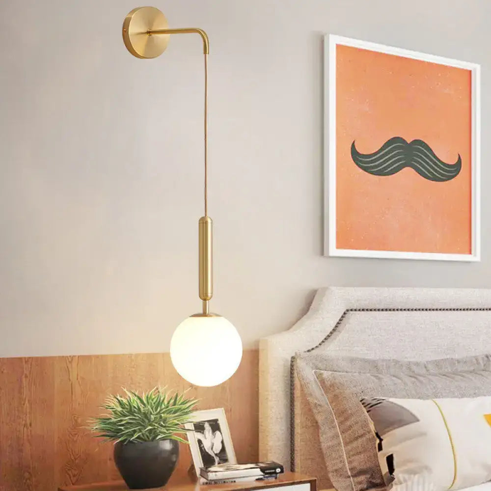 Gold-toned black gold minimalist wall sconce with curved arm and glass globe, ideal 8 inch fixture for bedroom lighting