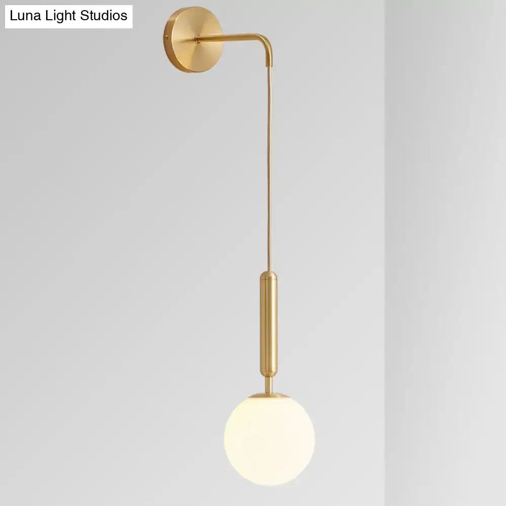 Minimalist black gold wall-mounted sconce with a gold finish, curved arm, and frosted glass globe 8-inch fixture
