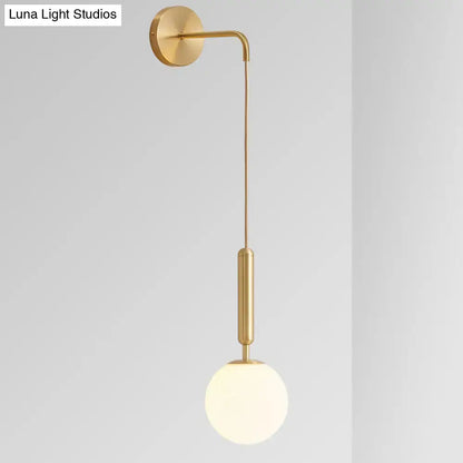 Minimalist black gold wall-mounted sconce with a gold finish, curved arm, and frosted glass globe 8-inch fixture