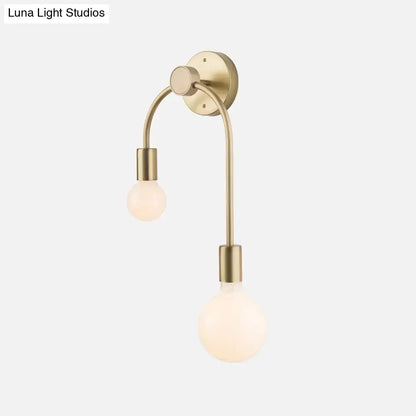 Brass-finished wall lamp with two curved arms holding frosted glass globe bulbs for minimalist bedroom decor