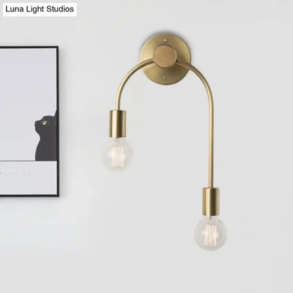 Minimalist black and brass wall lamp with two curved arms and clear glass filament bulbs for bedroom lighting