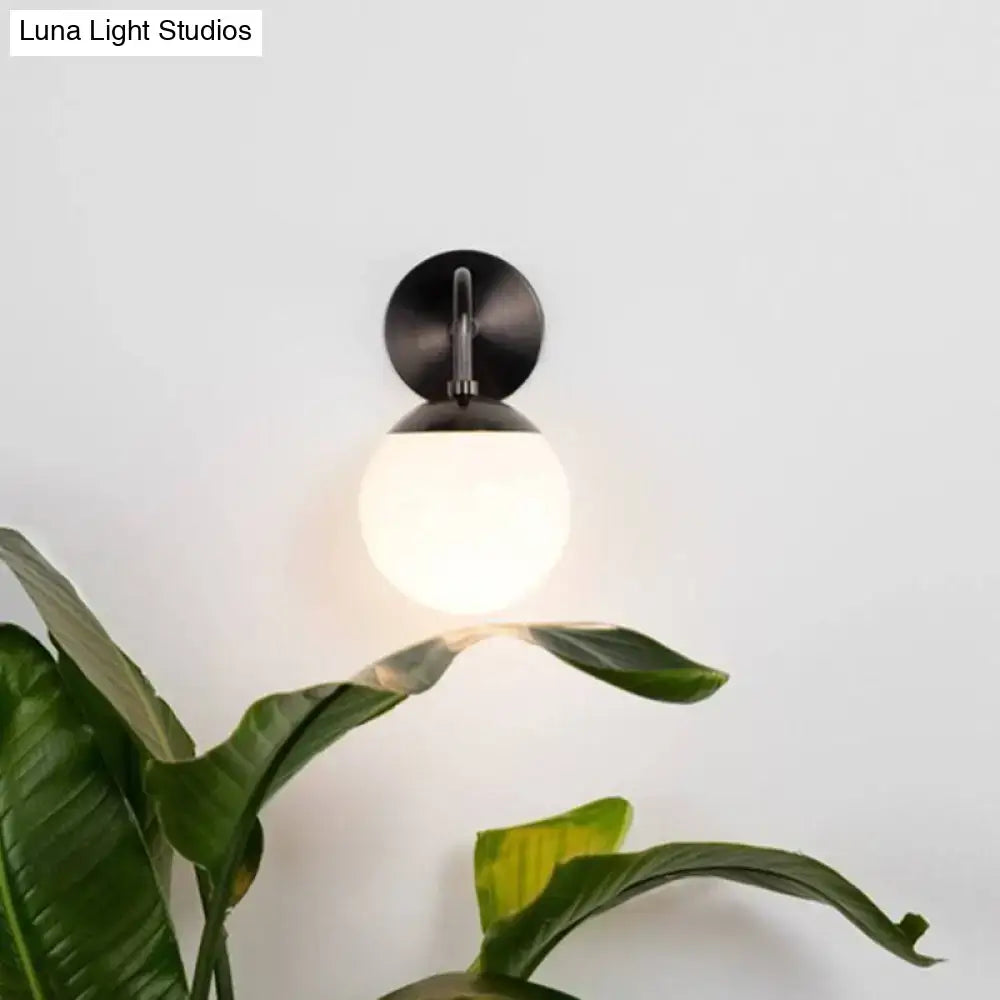 Minimalist golden black wall light with black matte finish and milky glass ball designed for bedroom use
