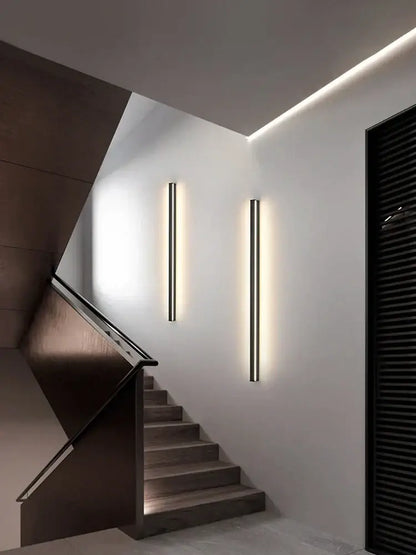 Two sleek minimalist black linear led wall lamps emit warm glow on white bedroom wall for ambient lighting