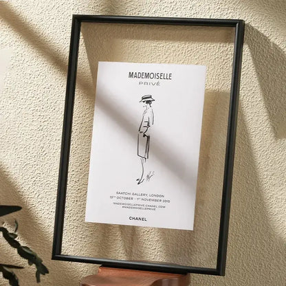Black-framed minimalist hangable picture frame featuring chanel mademoiselle privé line drawing art on white paper