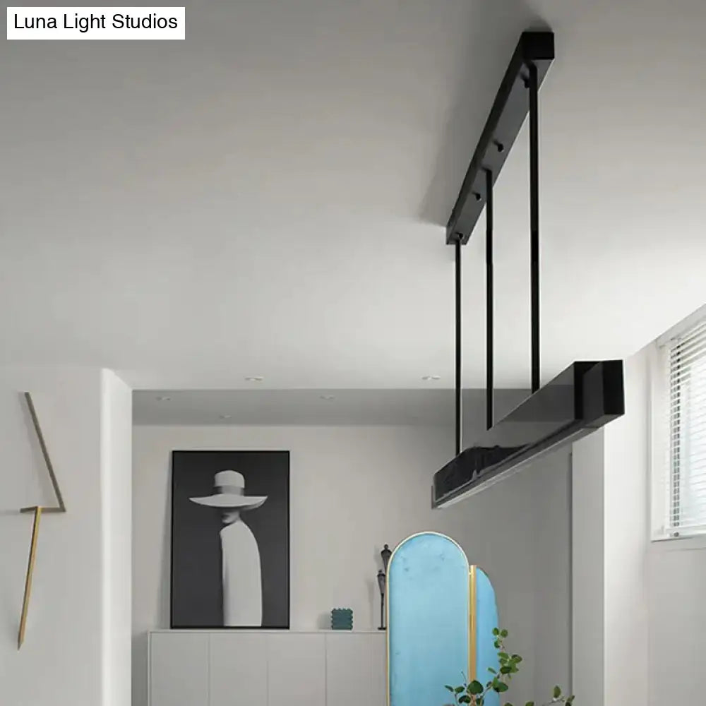 Modern black linear pendant light with minimalist design, matte finish, gold accents, and black cord for dining rooms