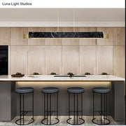 Minimalist black marble rectangular pendant light with gold accents and gold metal details hanging from black cord