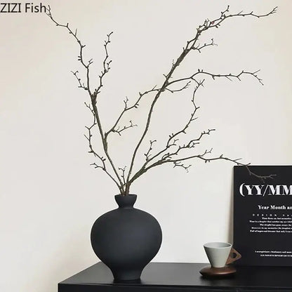 Minimalist black matte big belly ceramic vase with slender branches arranged for living room decor