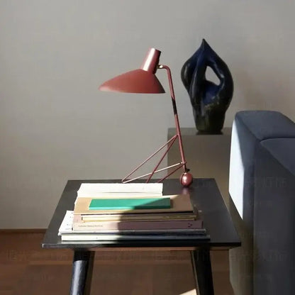 A sleek rose-gold desk lamp with a minimalist geometric base and conical shade for bedroom or office use