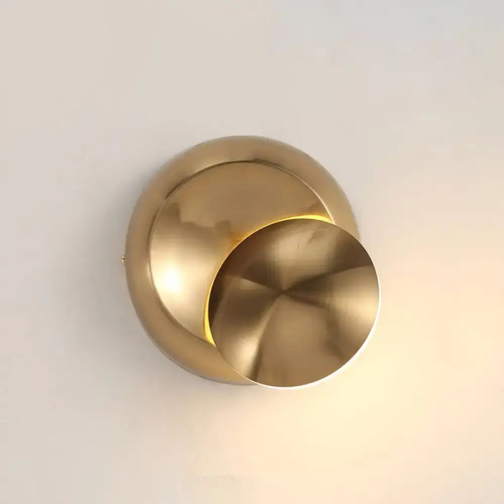 Brass-toned circular moon shaped sconce lighting with sleek overlapping disc design for minimalist bedroom wall lamp