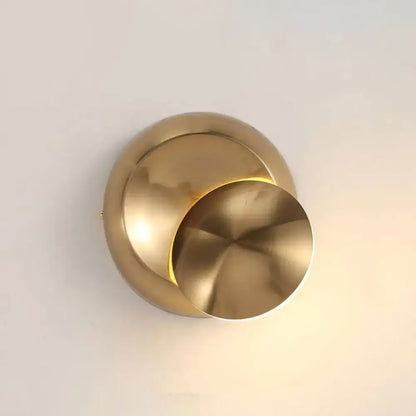 Brass-toned circular moon shaped sconce lighting with sleek overlapping disc design for minimalist bedroom wall lamp