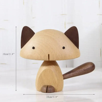 A minimalist wood carving figurine of a light wood cat with black bead eyes and dark brown ears tail and paws for living room decor